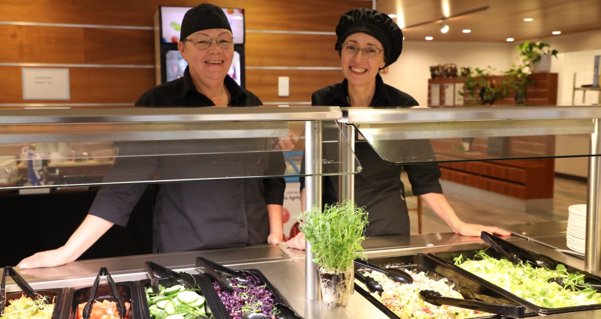 Kaksi työntekijää salaattilinjaston takana